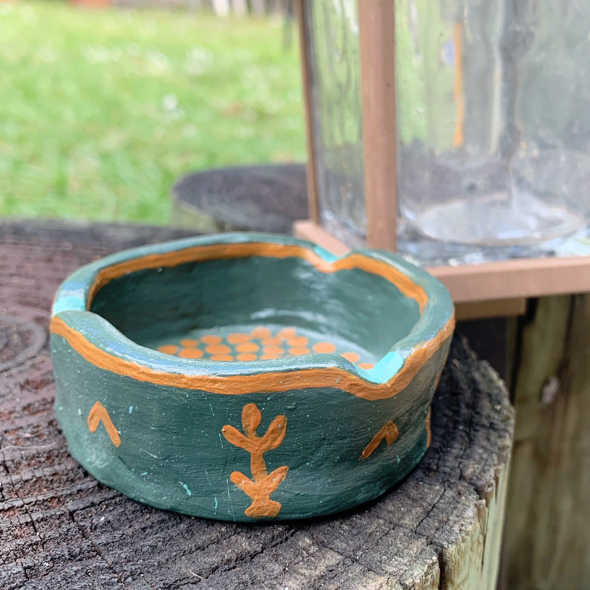 Ceramic dish with green glaze and orange accents on a wooden surface