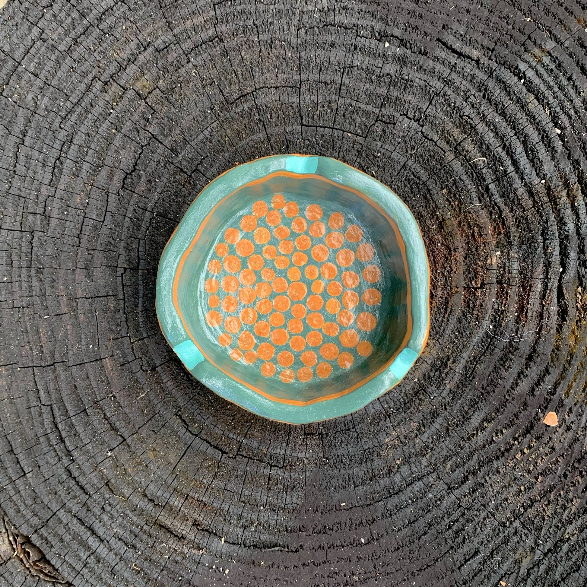 Teal ceramic dish with orange dots on a wooden surface