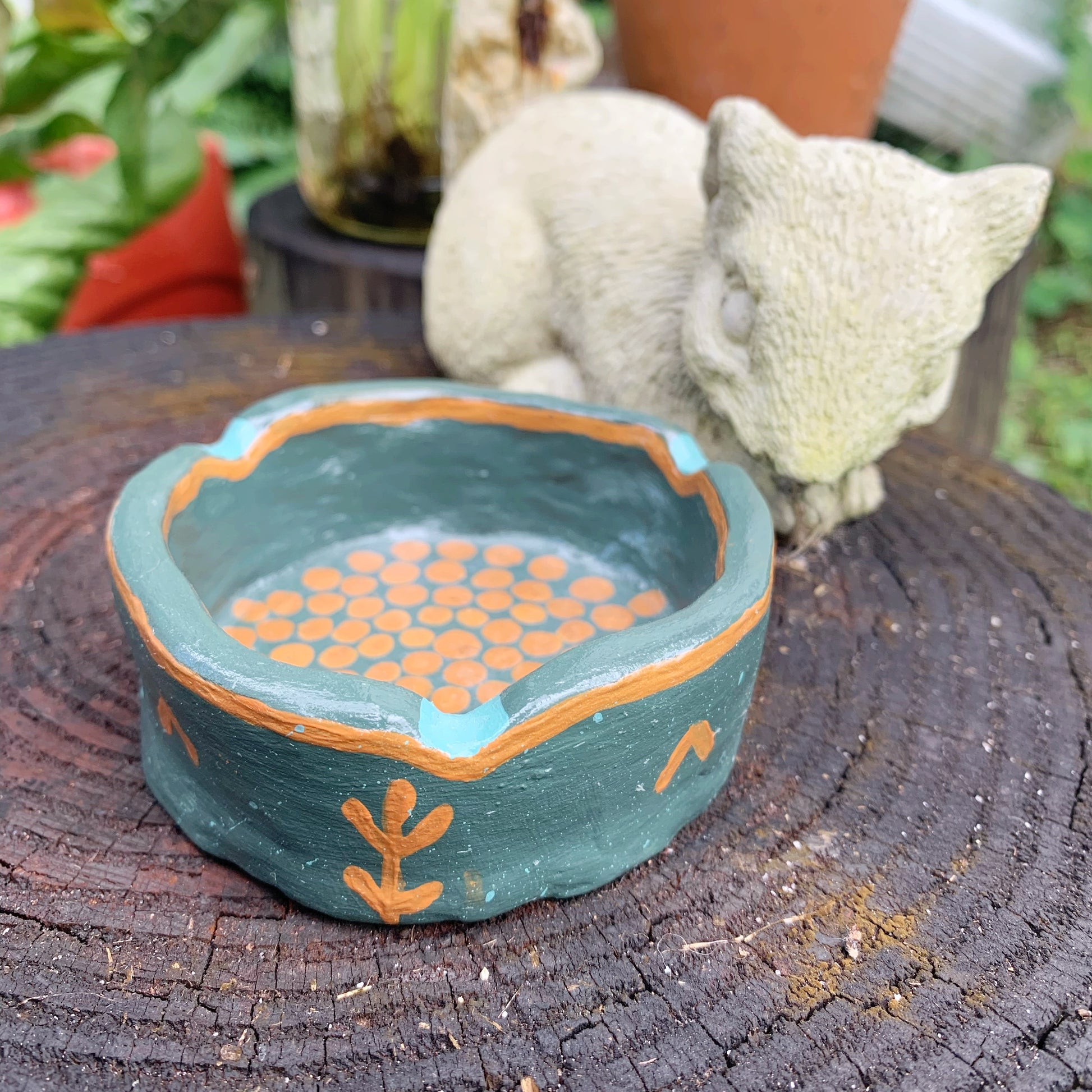 Small decorative bowl with orange beads on a wooden surface, with a squirrel figurine in the background.