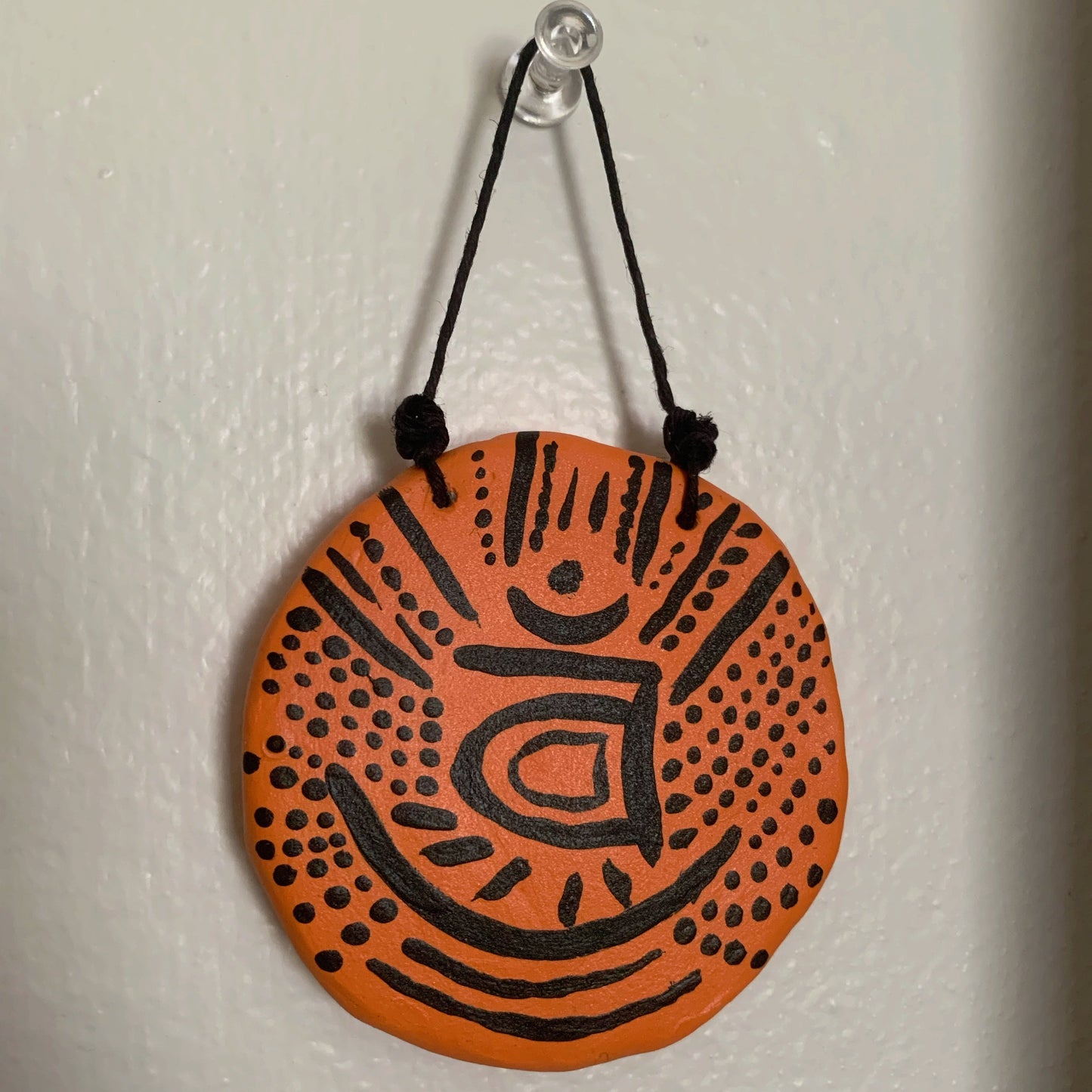 Round orange and black decorative item hanging on a white wall