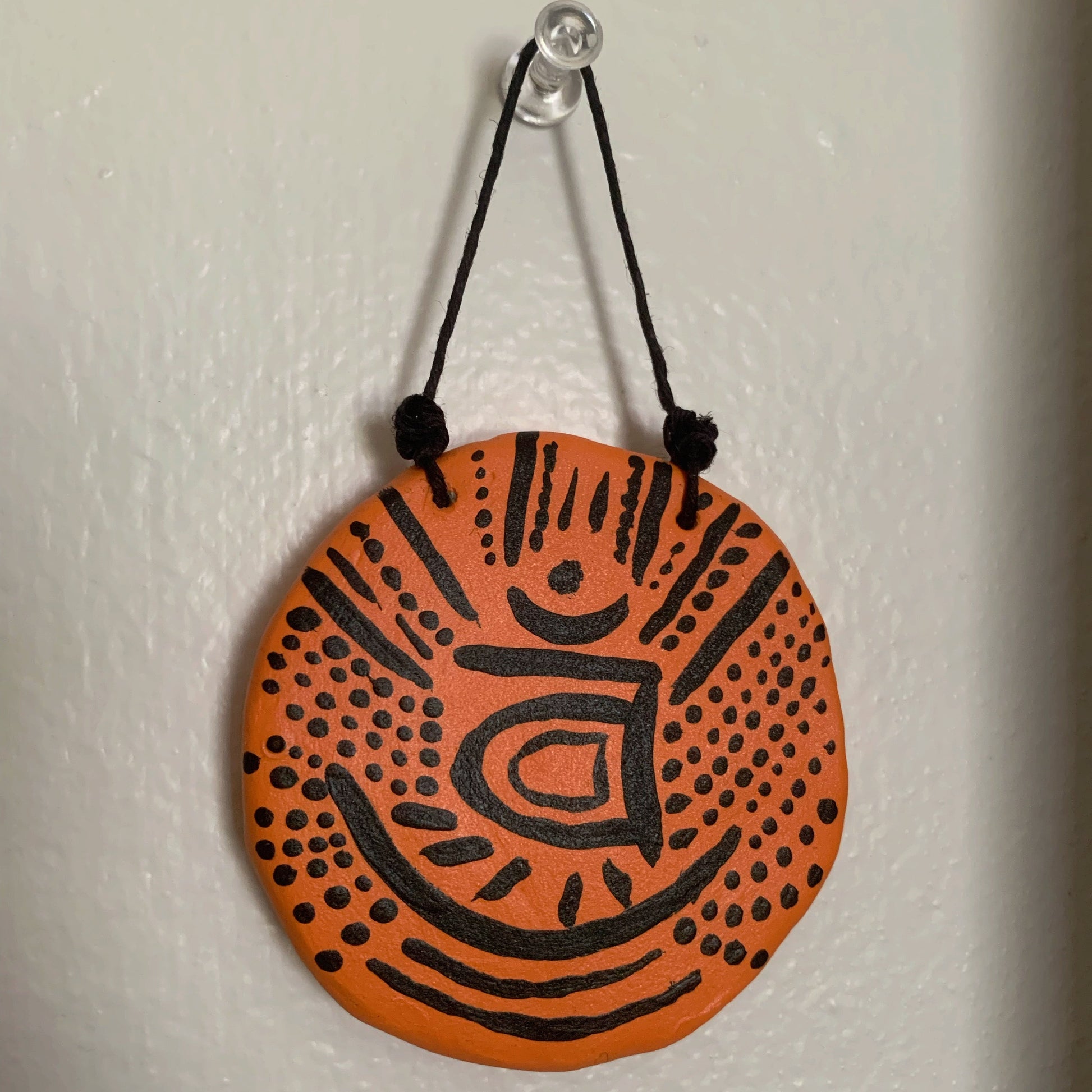 Round orange and black decorative item hanging on a white wall