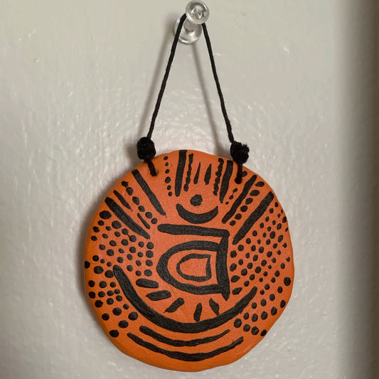 Round orange and black decorative item hanging on a white wall
