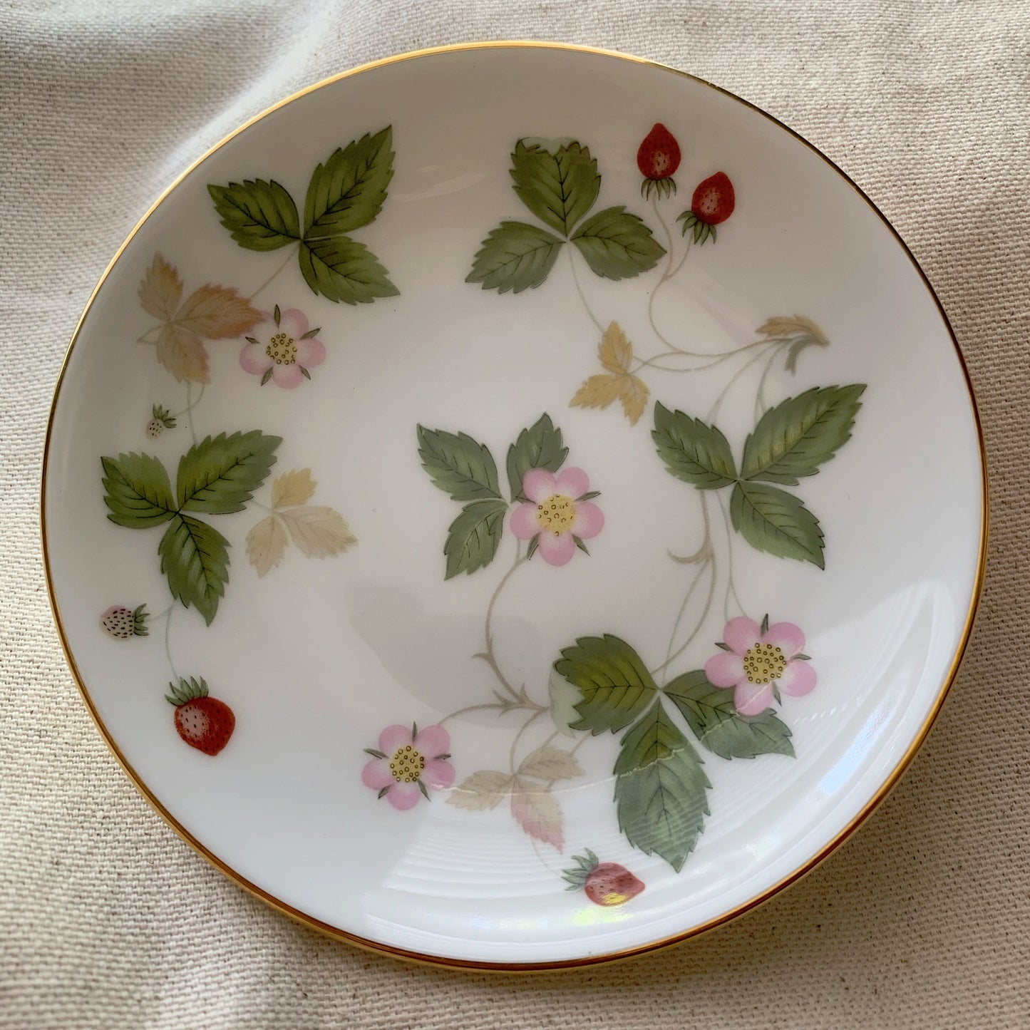Decorative plate with floral and leaf patterns on a beige fabric background