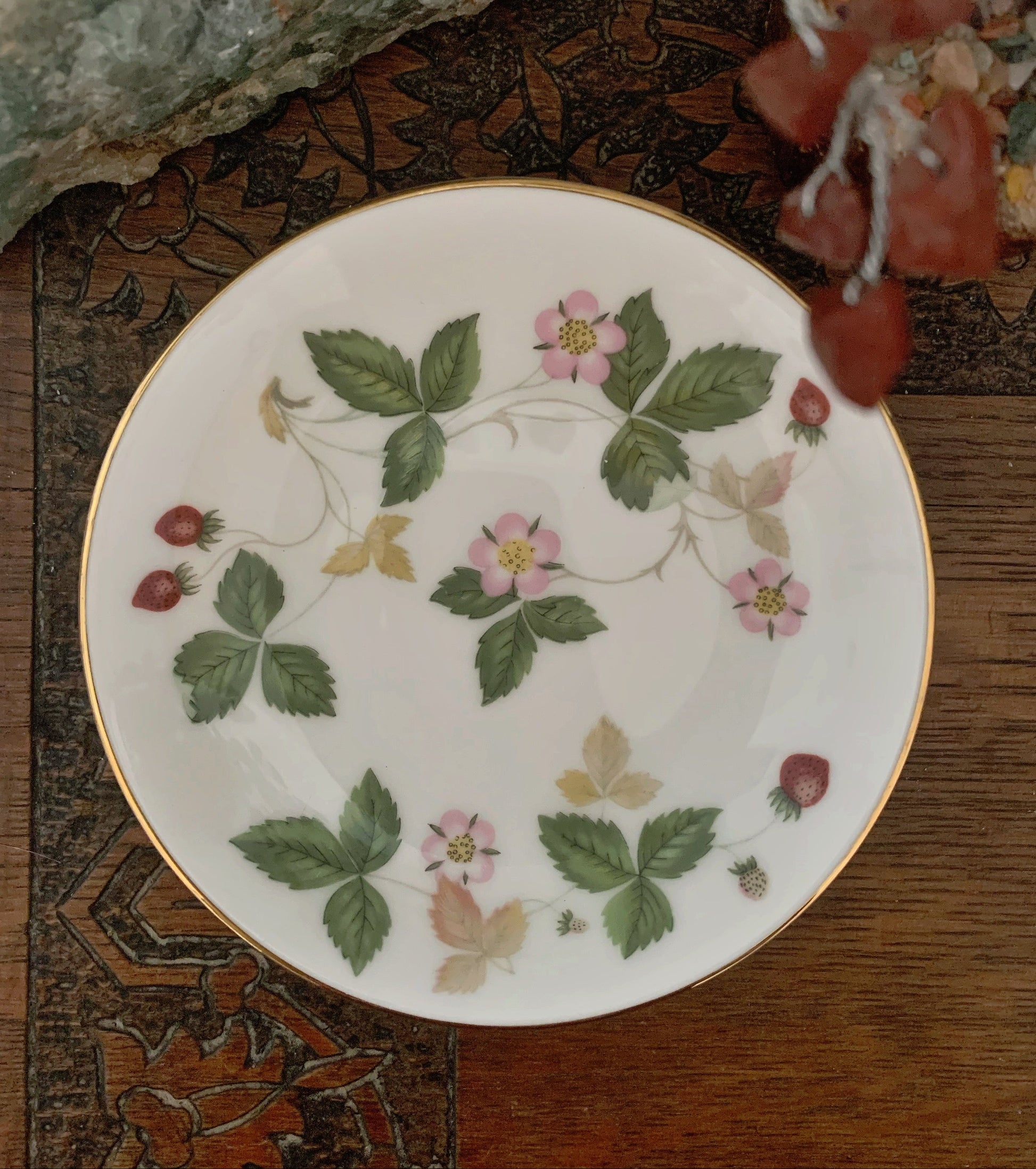 Decorative plate with floral and leaf patterns on a wooden surface